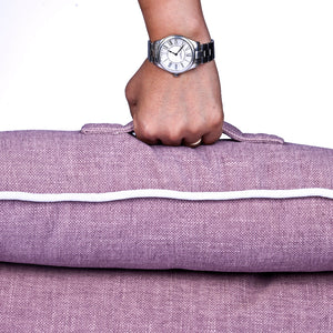 a hand holding the rhubarb dog bed with the handle
